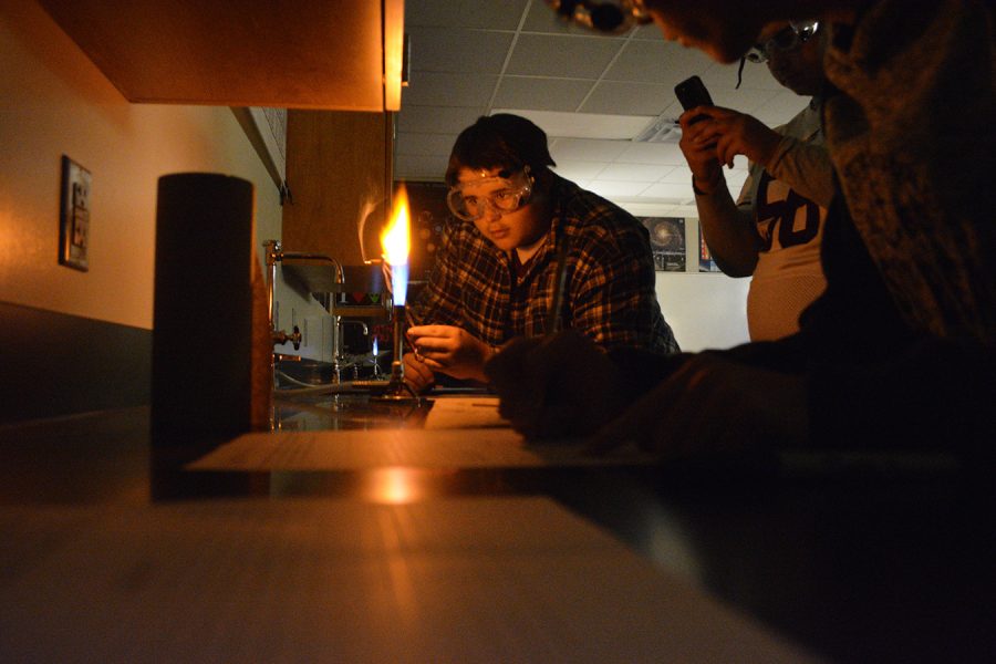 Junior Andrew McMurtry is placing a metal dipped stick into the lab burner during their experiment.