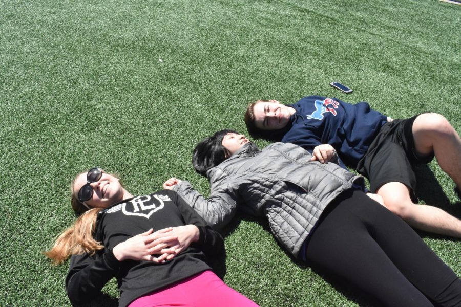 Taryn Moore, Lily Truong and Kyle Struble lounge on the turf after the softball throw competition. When planning the event, the comfort of athletes was a top priority.