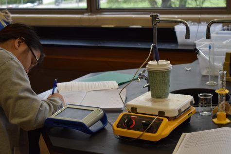 Ann Vu records a the measurements for a lab in AP chemistry 