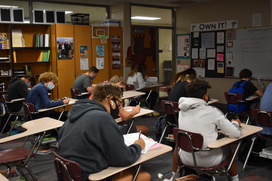 Students take notes during class while taking precautions against Covid-19