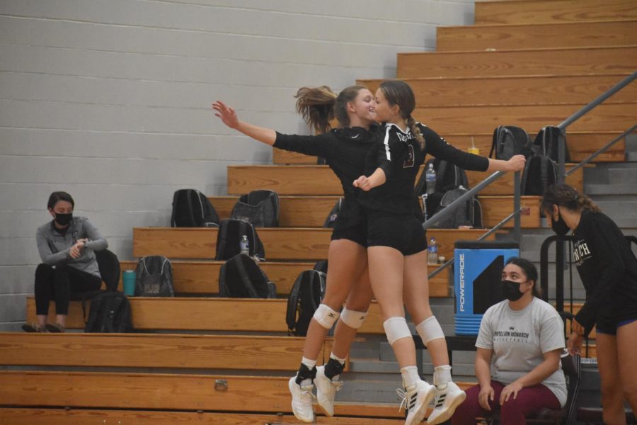 Senior Karli Ahlers and junior Anna Sis celebrate on the bench with a chest bump. 