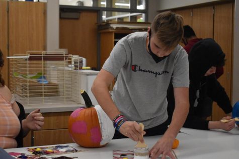 Freshman Max Yeshnowski works with his two friends to make a halloween theme pumpkin.