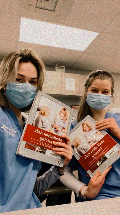 Seniors Haley Puhalla and Kristine Spearman pose with the textbook for their CMA class at the Health Academy. 