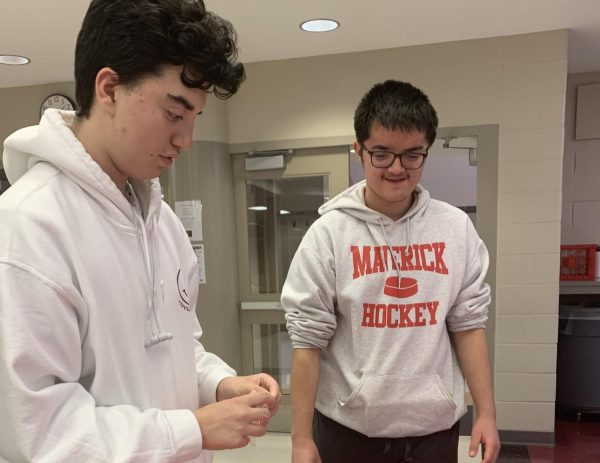 Junior Henry Hernandez and Junior Isaiah Horejs build a gingerbread house at the "friendsgiving" celebration. 