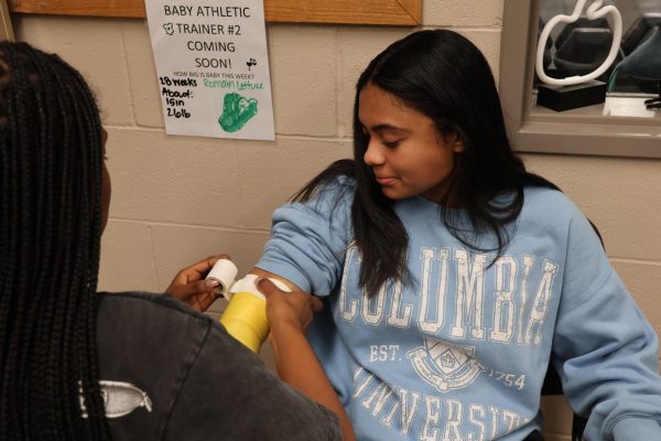 Junior Akelia Ferguson practices her taping skills during class on junior Maleya Crawford.