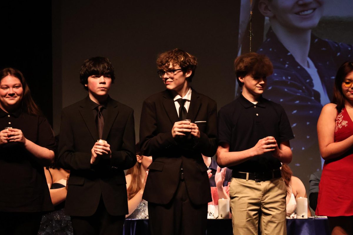 Junior Kaleb Chereck, junior Noah Finn and freshman Daniel Manley hold their candles during the International Thespian Society induction ceremony on May 6. The inductees take an oath to become a part of ITS Troupe 68.