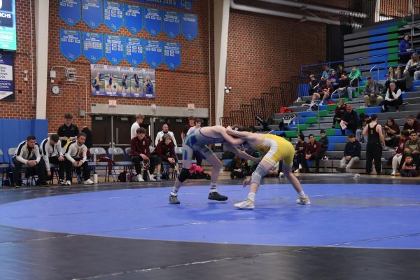 Coach Curtis Miller watches from the bench as Junior Wrestler Maverick Kidd upsets a Millard North wrestler