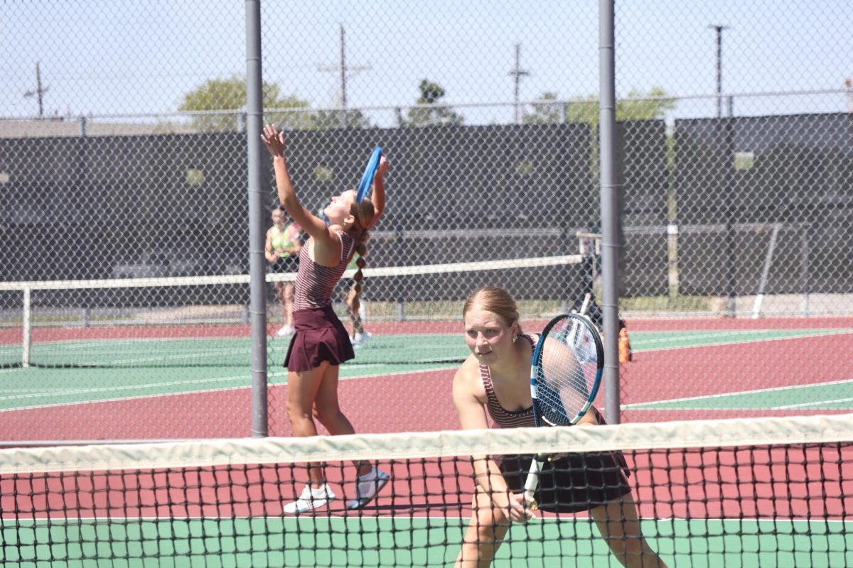 Senior Reagan Jorczak serves the ball while senior Catherine Chandler prepares at the net. These two played together in several double matches throughout the season.